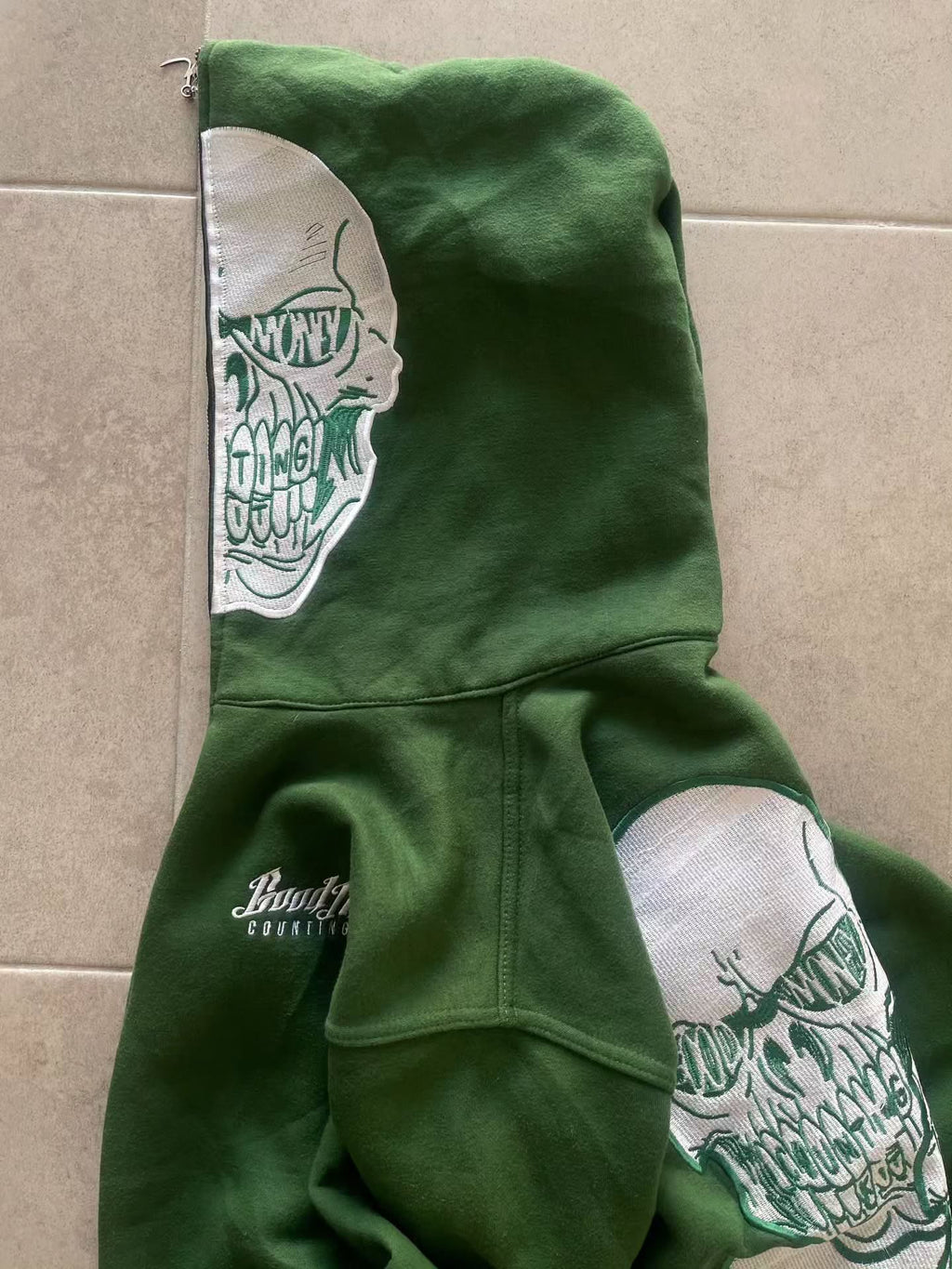 forest green full-zip hoodie (a "full-face zip" style) loaded with heavy, edgy Y2K/streetwear graphics and bold skull motifs