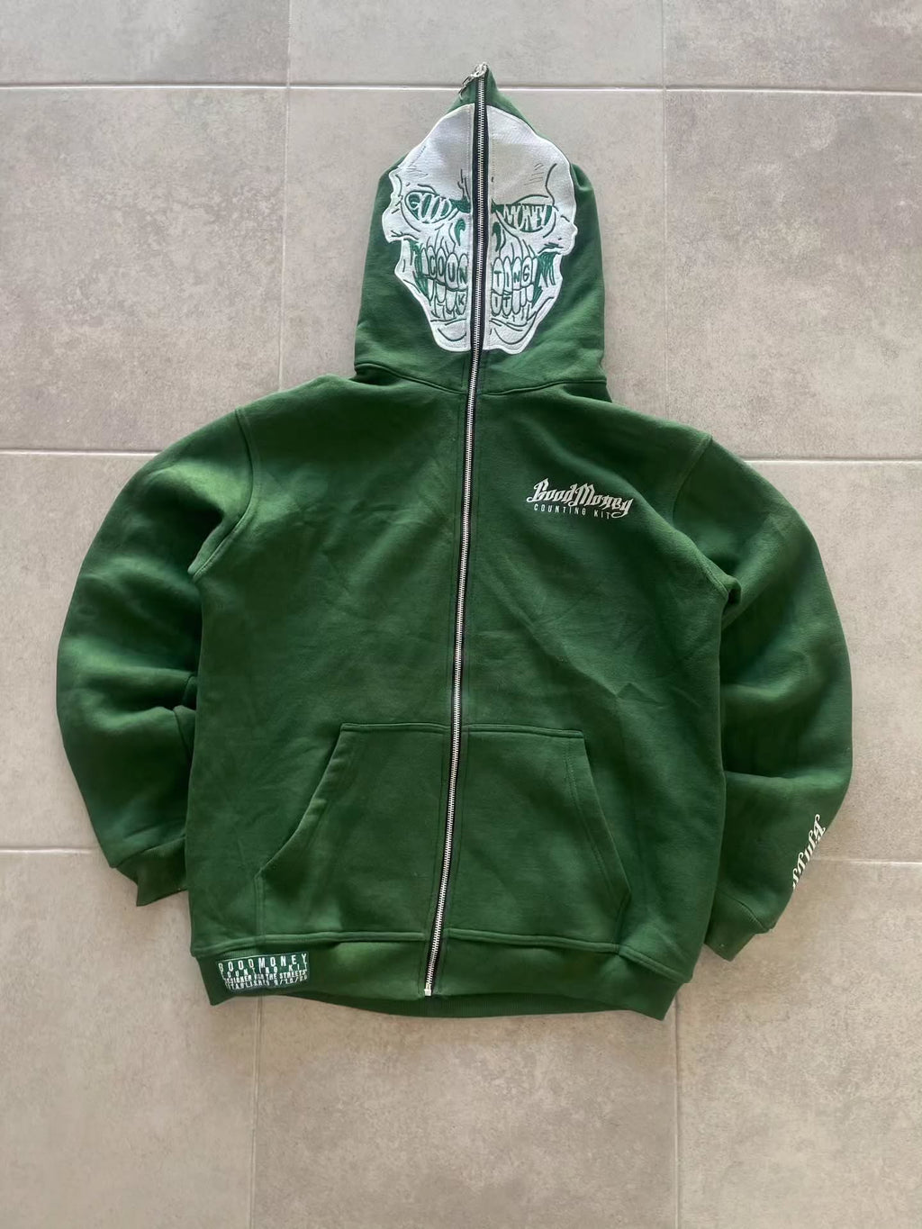 forest green full-zip hoodie (a "full-face zip" style) loaded with heavy, edgy Y2K/streetwear graphics and bold skull motifs
