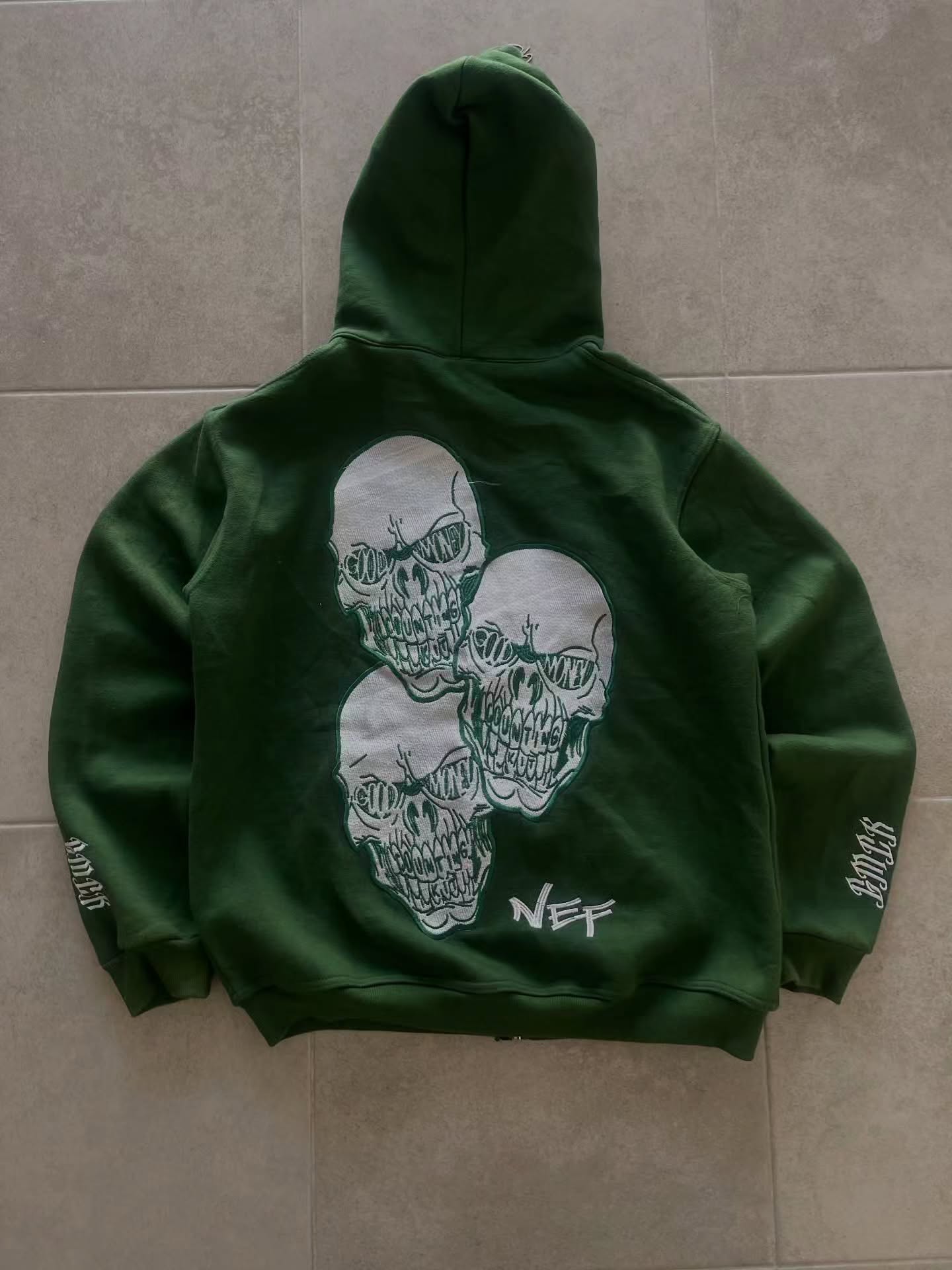 forest green full-zip hoodie (a "full-face zip" style) loaded with heavy, edgy Y2K/streetwear graphics and bold skull motifs