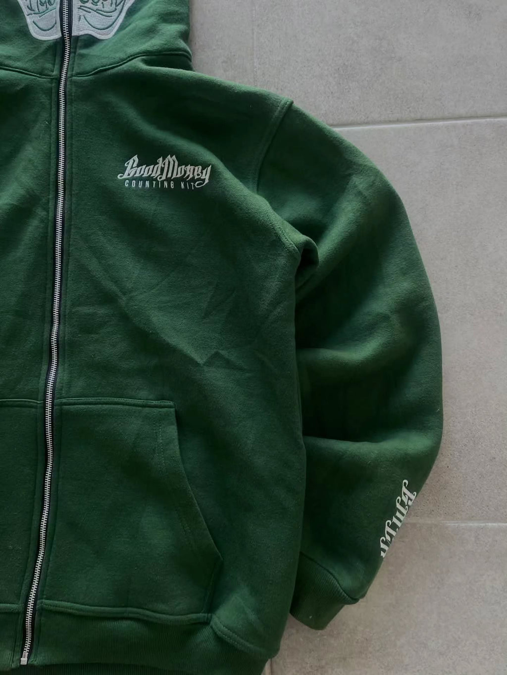 forest green full-zip hoodie (a "full-face zip" style) loaded with heavy, edgy Y2K/streetwear graphics and bold skull motifs