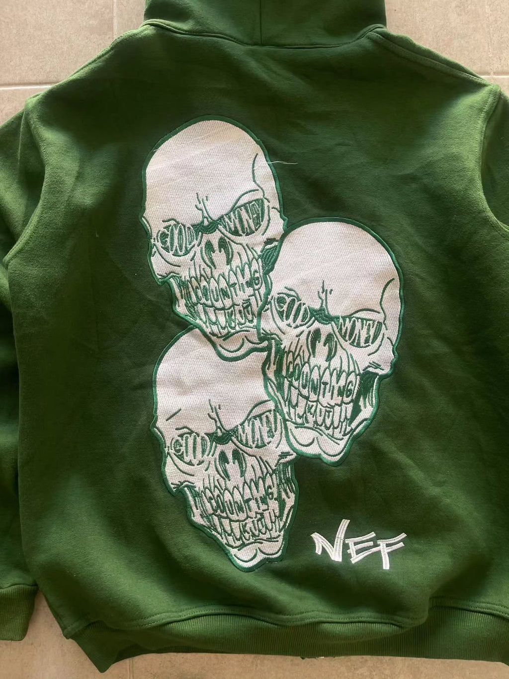 forest green full-zip hoodie (a "full-face zip" style) loaded with heavy, edgy Y2K/streetwear graphics and bold skull motifs