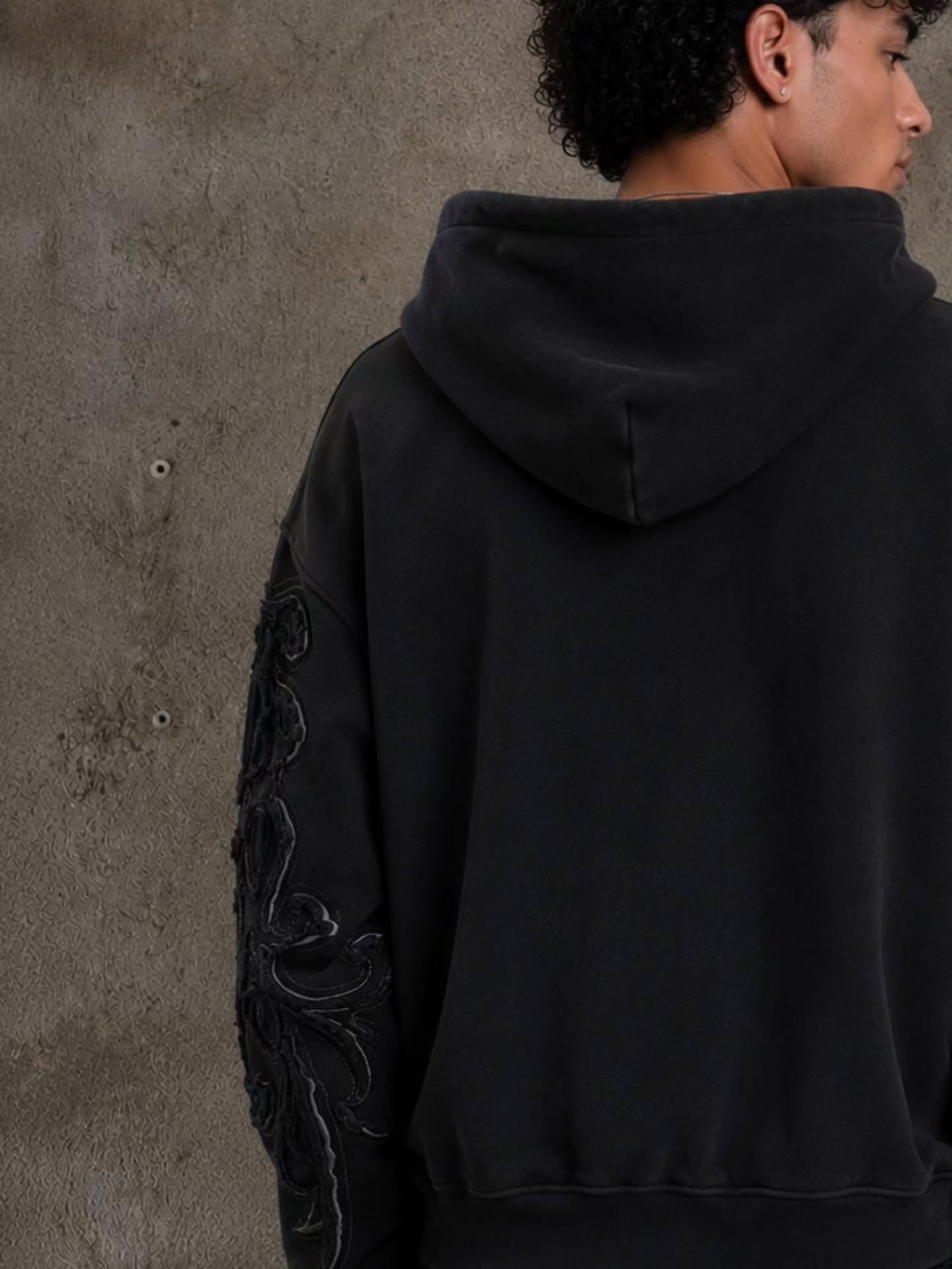 faded washed-black full-zip hoodie featuring heavy raw-edge applique patches and contrast embroidery