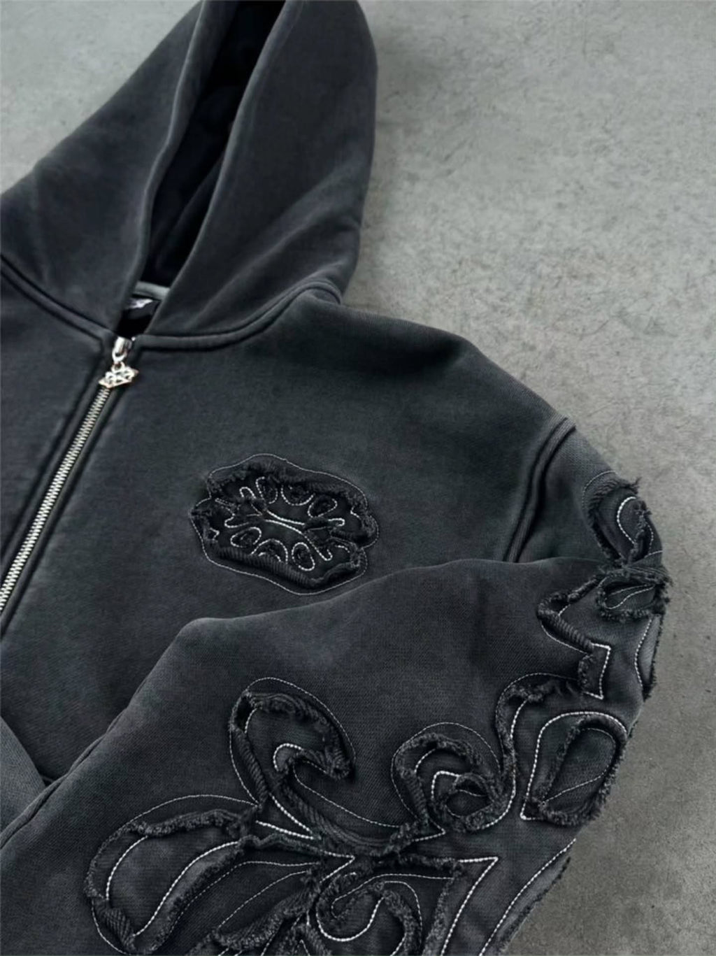faded washed-black full-zip hoodie featuring heavy raw-edge applique patches and contrast embroidery