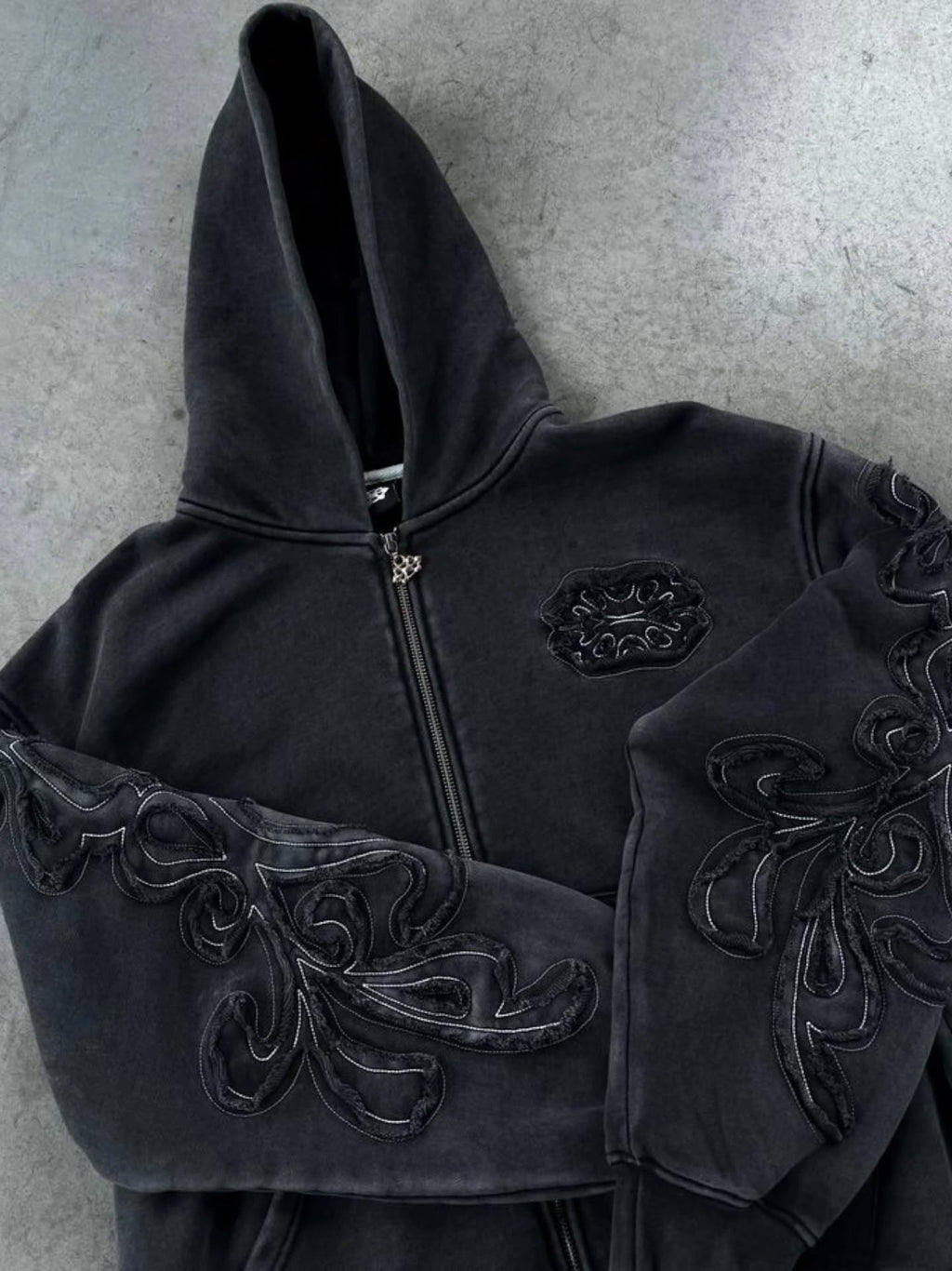 faded washed-black full-zip hoodie featuring heavy raw-edge applique patches and contrast embroidery
