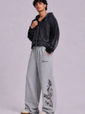 boxy, oversized streetwear outfit pairing a cropped acid-washed zip hoodie with wide-leg graphic sweatpants for a relaxed, Y2K-inspired silhouette.